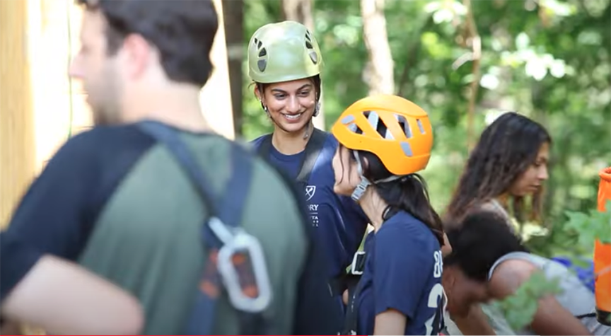 students wearing helmets on a ropes course smiling