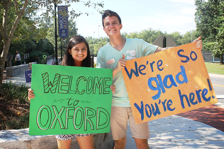 two students holding welcome signs at oxford college
