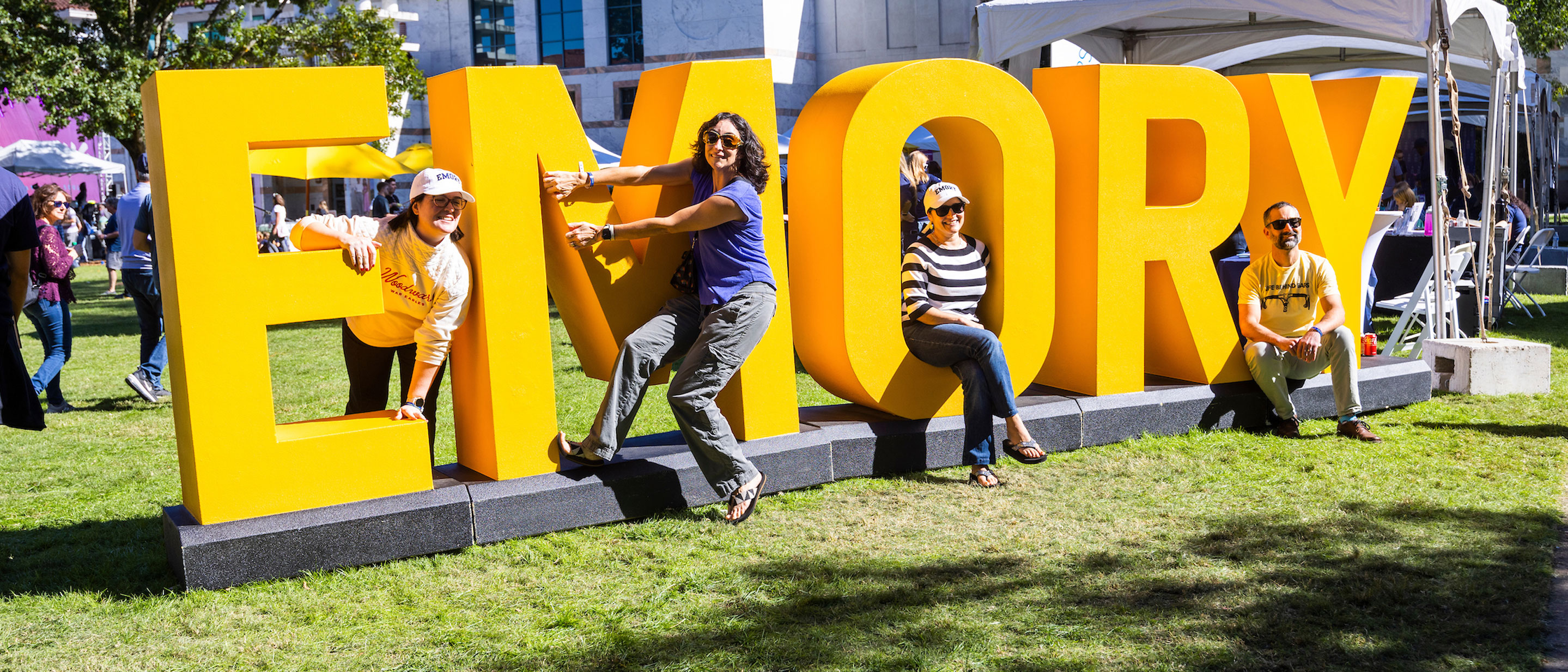 families pose by the big yellow emory letters