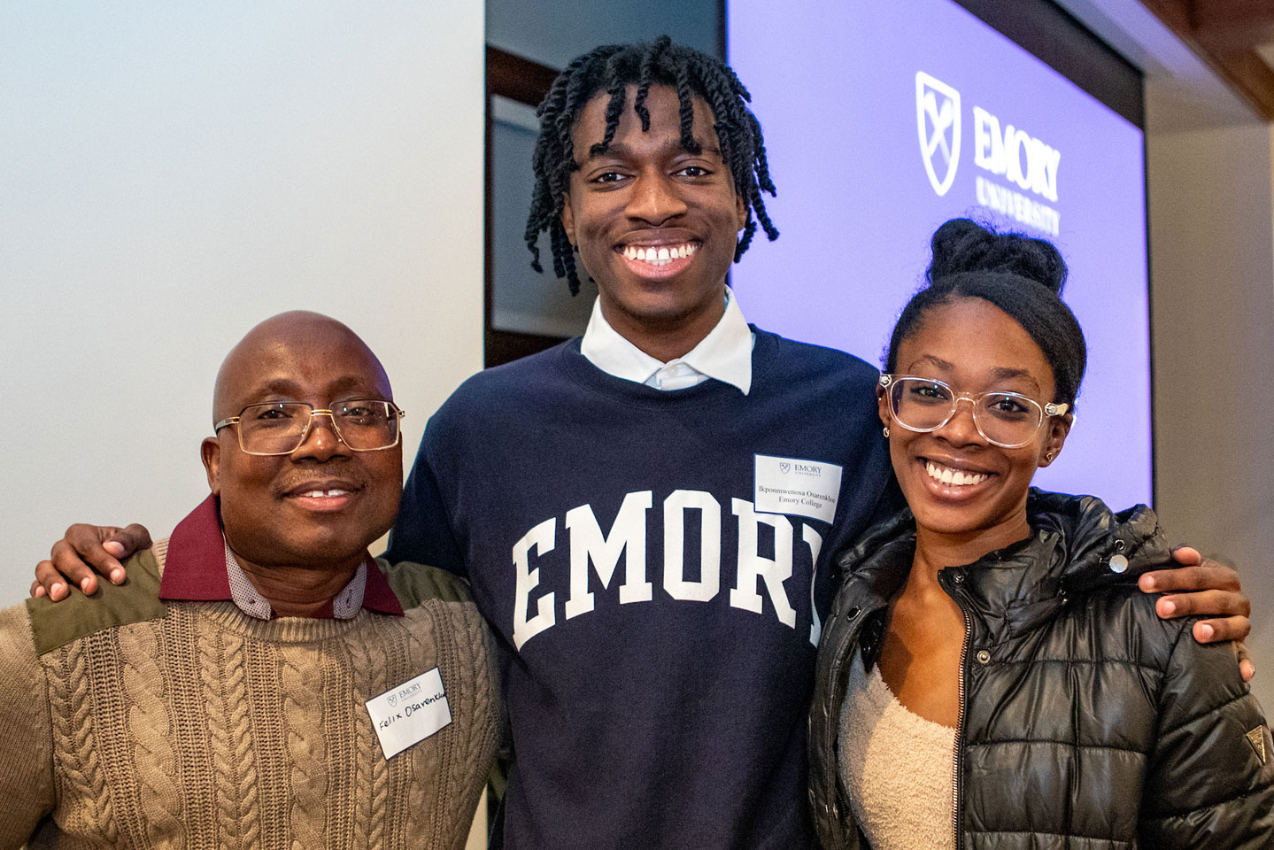 a smiling family poses together at family weekend